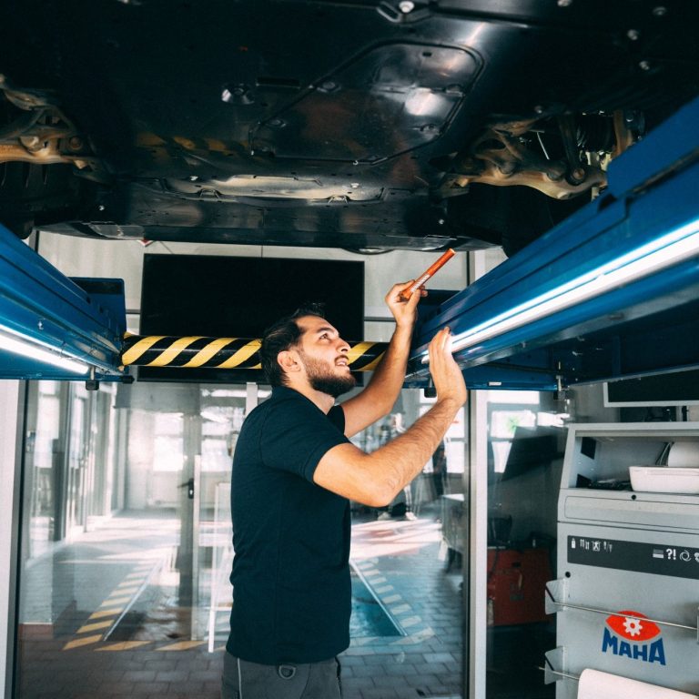 Ein Mechaniker inspiziert ein Fahrzeug unter einer Hebebühne.