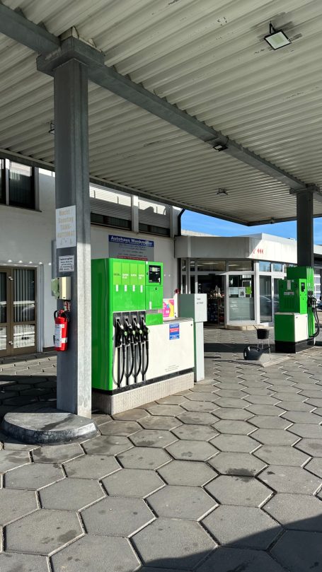 Grüne Tankstelle mit Geldautomaten und Eingang zur Tankstelle, sonniger Tag, neues Gebäude.