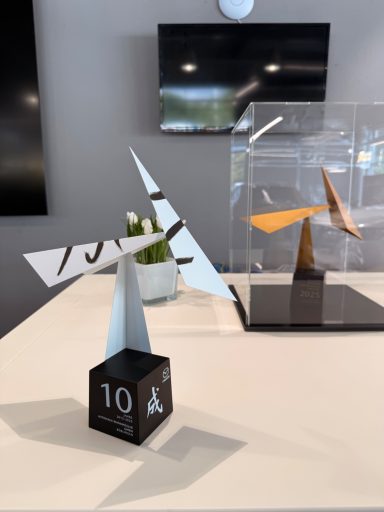 Skulptur mit geometrischen Formen auf einem Tisch, neben einer weiteren Skulptur. Es stellt den 10 Jahre Jubiläums Preis von Mazda dar.