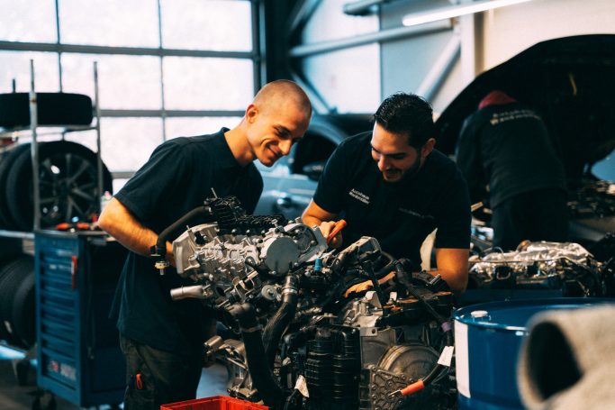 Zwei Mechaniker arbeiten konzentriert an einem Motor in einer Werkstatt.