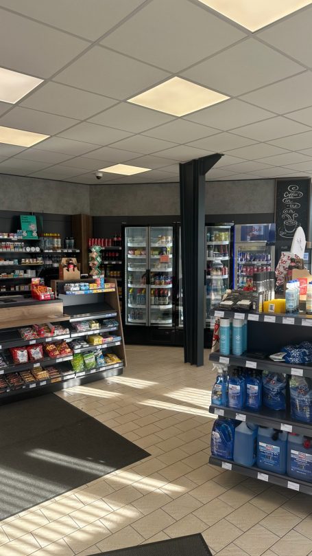 Der Innenraum der Tankstelle mit dem Tankstellen-Shop inklusive Regalen, Kühlschränken und hellem Licht.